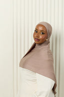 Woman wearing a brown hijab and white outfit against a white background